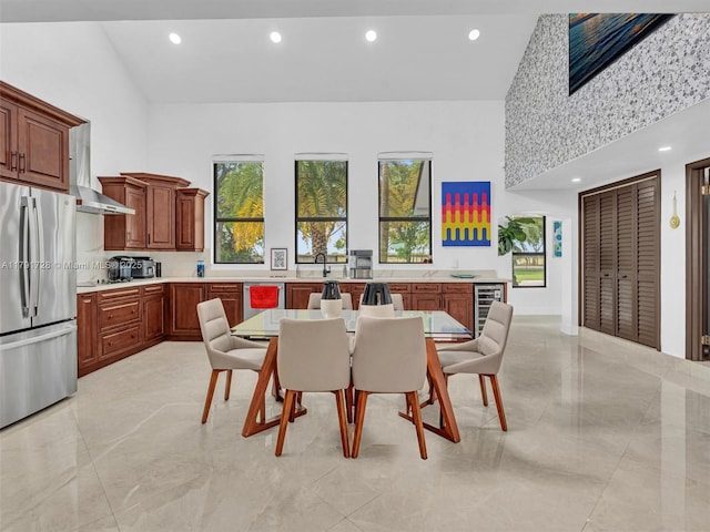 dining space featuring a high ceiling, recessed lighting, beverage cooler, and marble finish floor