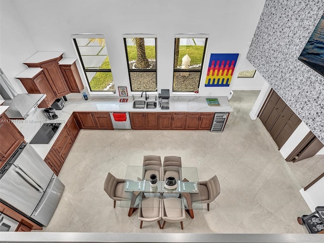 kitchen with brown cabinets, a sink, light countertops, black electric cooktop, and stainless steel dishwasher