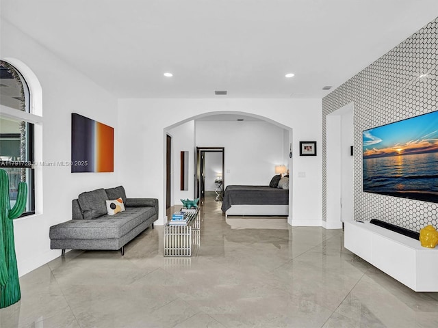 bedroom featuring arched walkways, baseboards, recessed lighting, and an accent wall