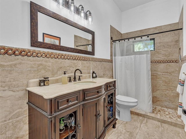 bathroom featuring vanity, toilet, tile walls, tiled shower, and a wainscoted wall