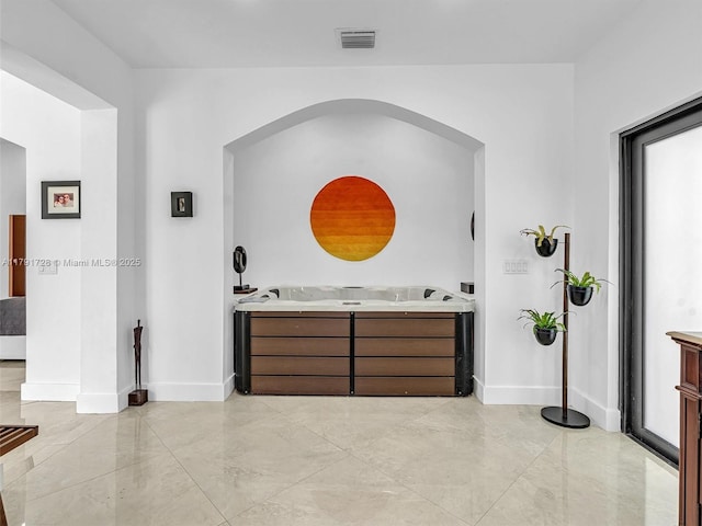interior space featuring visible vents, arched walkways, baseboards, and marble finish floor