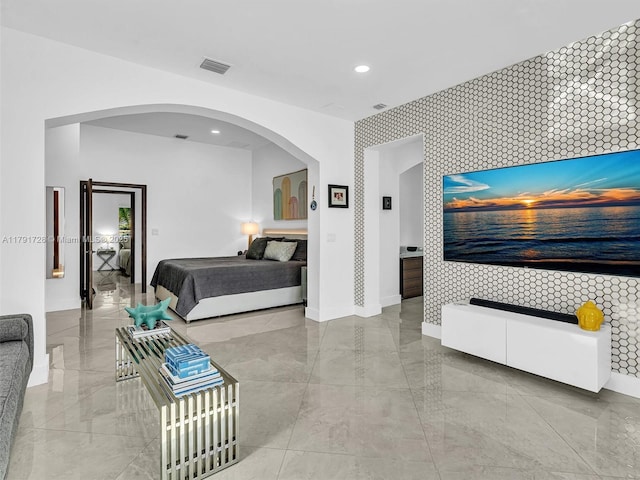 bedroom with arched walkways, an accent wall, marble finish floor, baseboards, and visible vents