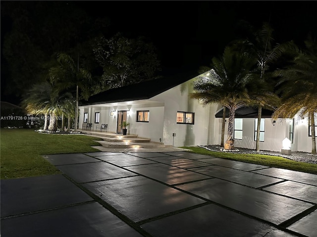 view of front of house featuring a yard, a patio area, and stucco siding