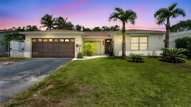 single story home featuring an attached garage, a yard, stucco siding, and driveway
