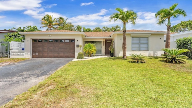 ranch-style home featuring a garage, fence, a front yard, stucco siding, and driveway