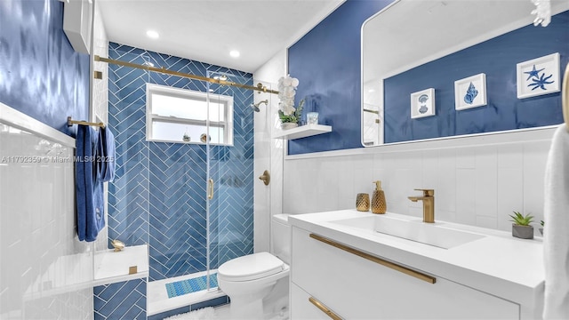 bathroom with wainscoting, vanity, toilet, tile walls, and a shower stall
