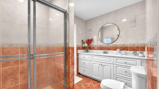 bathroom with toilet, tile walls, a shower stall, and vanity