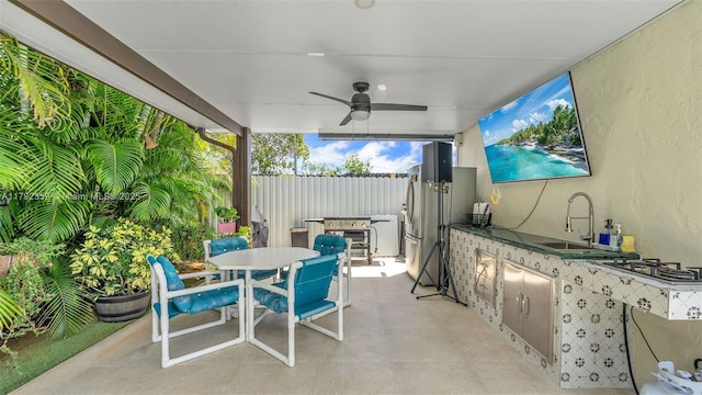 view of patio / terrace with fence, a sink, outdoor dining area, area for grilling, and a ceiling fan