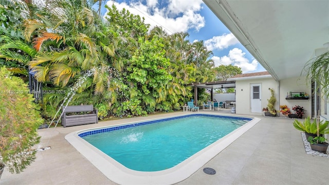 outdoor pool featuring fence and a patio