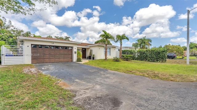 ranch-style home featuring an attached garage, aphalt driveway, a front lawn, and stucco siding