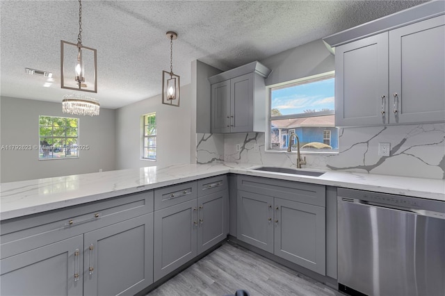 kitchen featuring stainless steel dishwasher, visible vents, light wood-style floors, a sink, and gray cabinetry