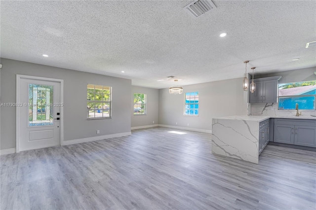 kitchen with gray cabinets, light wood-type flooring, and a textured ceiling