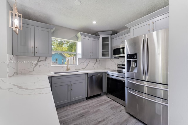 kitchen featuring a sink, a textured ceiling, appliances with stainless steel finishes, and gray cabinetry