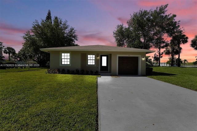 ranch-style house featuring a garage, stucco siding, driveway, and a front lawn