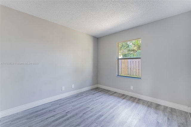 spare room with baseboards, a textured ceiling, and wood finished floors