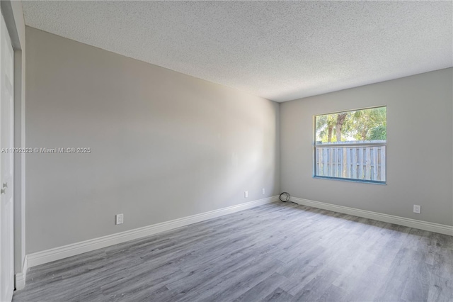 spare room with baseboards, a textured ceiling, and wood finished floors