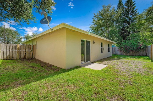 rear view of property with a fenced backyard, stucco siding, and a yard