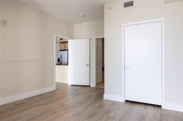 79 SW 12th St Unit 1403-S, Miami, FL 33130 - unfurnished bedroom with baseboards, visible vents, wood finished floors, and stainless steel fridge with ice dispenser