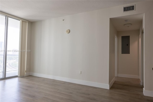 79 SW 12th St Unit 1403-S, Miami, FL 33130 - spare room featuring baseboards, light wood-type flooring, visible vents, expansive windows, and electric panel