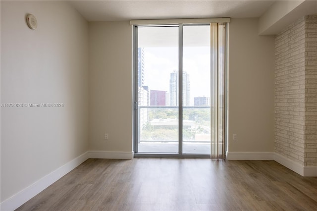 79 SW 12th St Unit 1403-S, Miami, FL 33130 - spare room with baseboards, a wall of windows, and wood finished floors