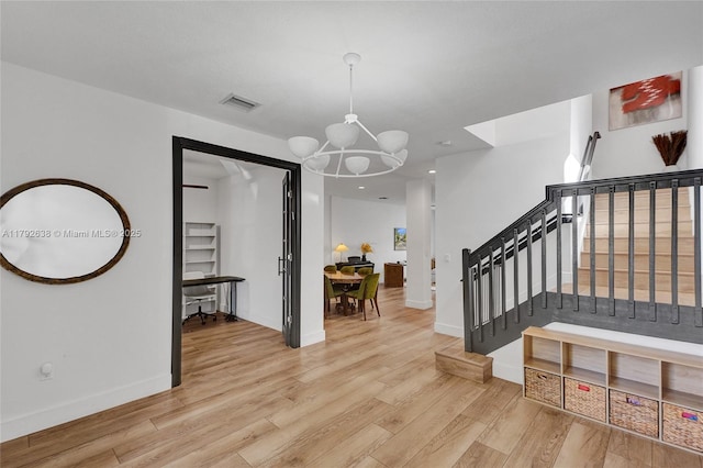 foyer featuring an inviting chandelier, light wood finished floors, stairs, baseboards, and visible vents