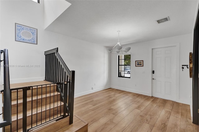 entrance foyer featuring stairs, baseboards, visible vents, and light wood-style floors