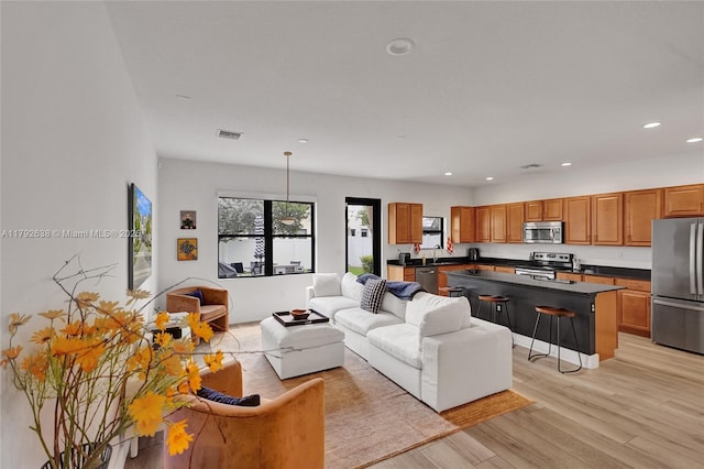 living area featuring light wood-style floors, recessed lighting, and visible vents