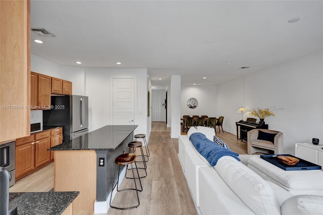 living room featuring visible vents, recessed lighting, and light wood finished floors