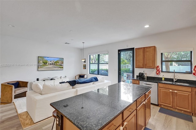 kitchen featuring a kitchen island, dishwasher, a sink, open floor plan, and recessed lighting