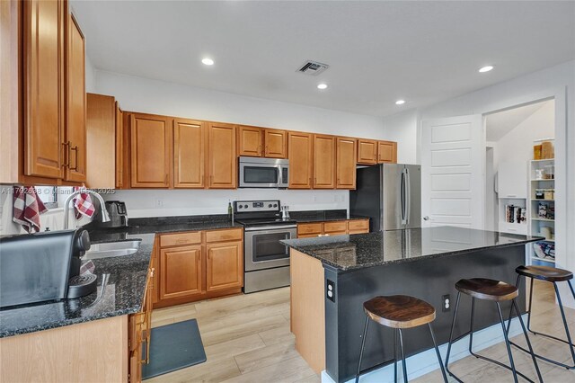 kitchen with dark stone counters, appliances with stainless steel finishes, a breakfast bar, and visible vents