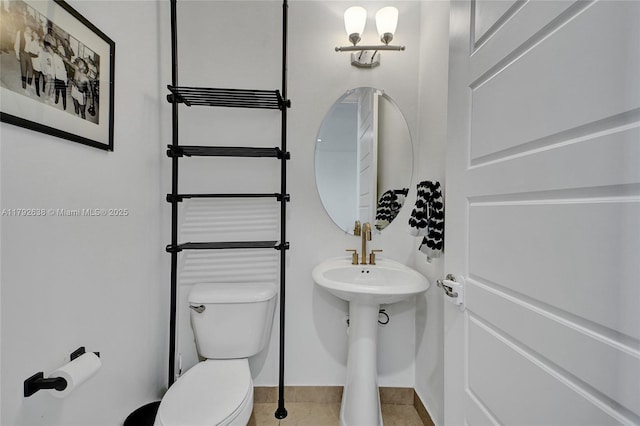 bathroom featuring baseboards, tile patterned flooring, and toilet