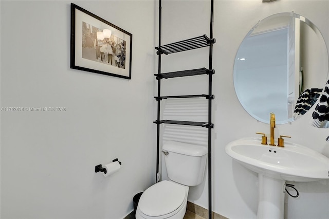 half bathroom featuring toilet and baseboards
