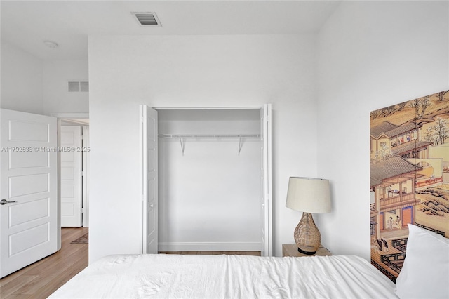 bedroom featuring visible vents, wood finished floors, and a closet