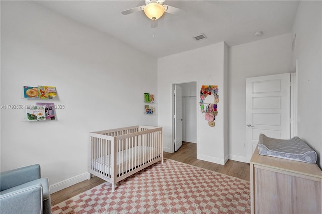 bedroom with baseboards, visible vents, and wood finished floors