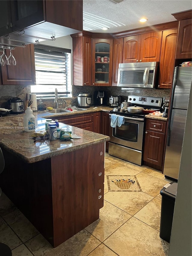 kitchen with a sink, decorative backsplash, stainless steel appliances, and a peninsula