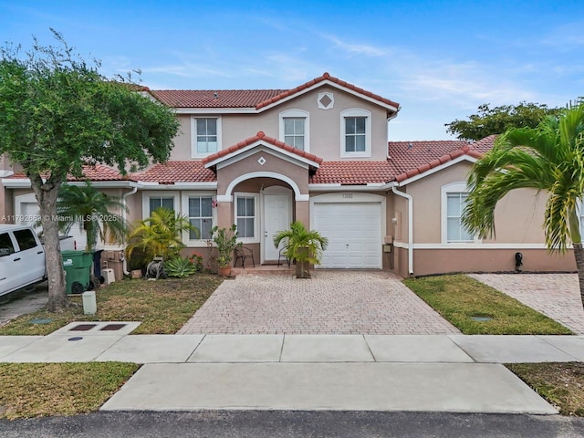 mediterranean / spanish-style house with driveway, a tile roof, and stucco siding
