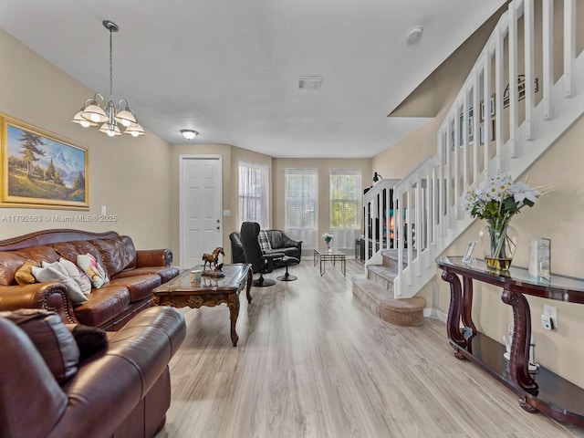 living room with visible vents, wood finished floors, stairway, baseboards, and a chandelier