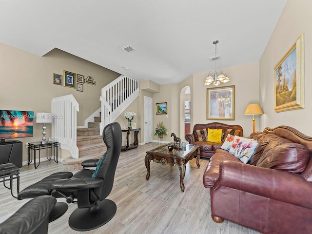 living area featuring arched walkways, visible vents, stairway, and light wood-type flooring