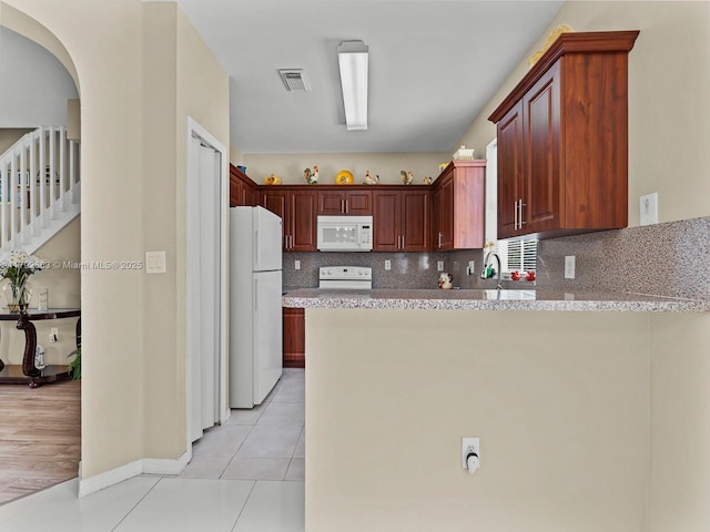 kitchen with white appliances, a peninsula, light tile patterned floors, backsplash, and visible vents