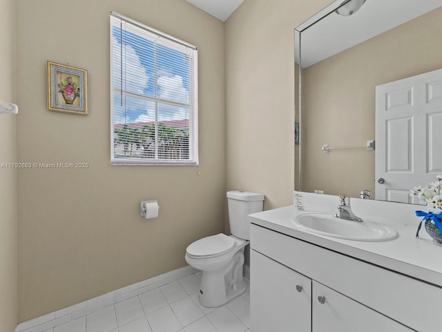 half bathroom with baseboards, tile patterned flooring, vanity, and toilet