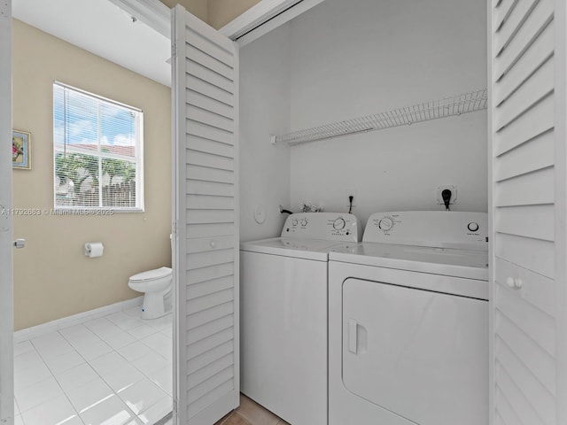 laundry area with baseboards, laundry area, washing machine and dryer, and light tile patterned flooring