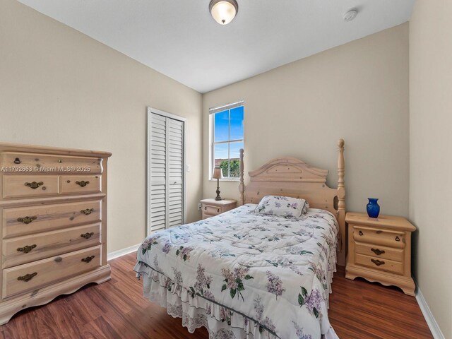 bedroom featuring baseboards, wood finished floors, and a closet