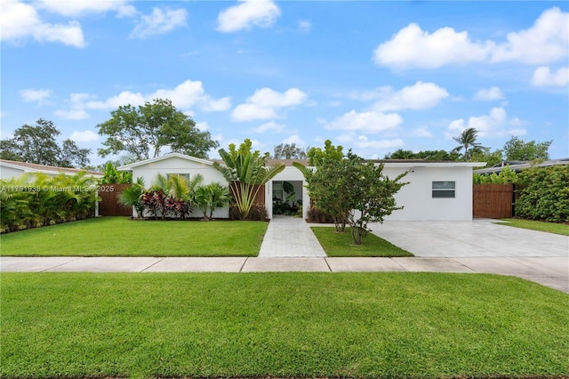 view of front of house with fence, stucco siding, driveway, and a front yard