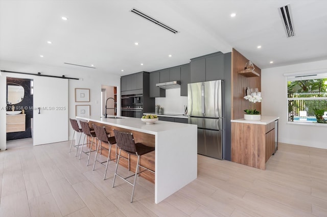 kitchen featuring visible vents, modern cabinets, a barn door, light countertops, and freestanding refrigerator