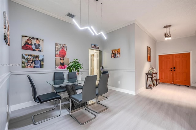 dining room with visible vents, ornamental molding, baseboards, and wood finished floors
