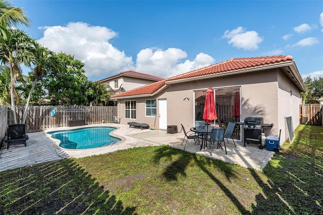 rear view of property with a fenced backyard, stucco siding, a yard, and a tiled roof