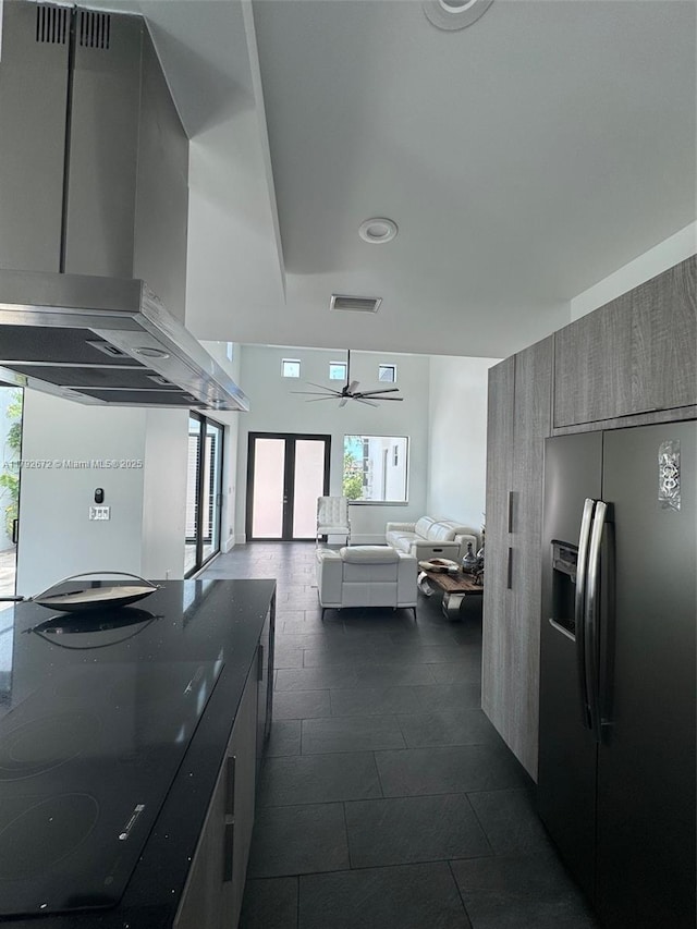 kitchen featuring wall chimney exhaust hood, open floor plan, fridge with ice dispenser, visible vents, and modern cabinets