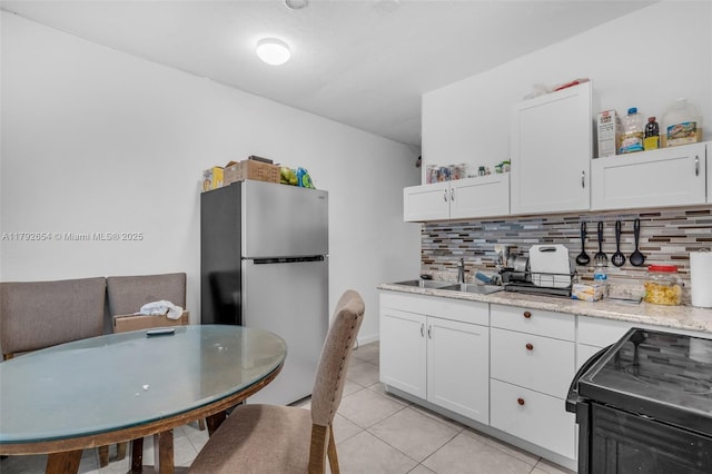 9000 NW 25th Ave, Miami, FL 33147 - kitchen featuring freestanding refrigerator, backsplash, and white cabinets