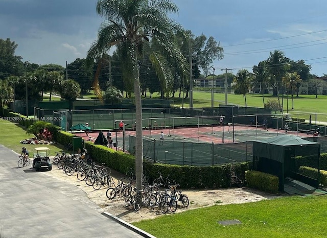 view of tennis court featuring a yard and fence