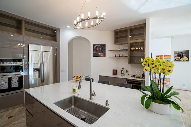 260 NE Wavecrest Ct, Boca Raton, FL 33432 - kitchen featuring stainless steel appliances, arched walkways, a chandelier, decorative light fixtures, and light stone counters
